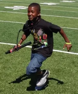 A young boy running on a football field with a laser tag tagger.