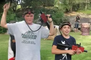 Two boys holding laser tag taggers in front of a group of people.