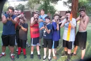 A group of boys posing for a picture with their laser tag taggers and gear.