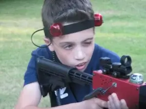A young boy holding a red laser tag tagger.