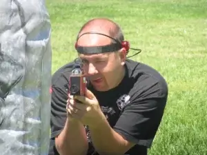 A man holding a laser tag tagger by a barrier.