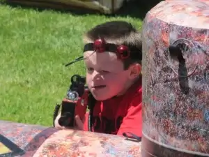 A young boy is playing with a laser tag tagger behind a barrier.