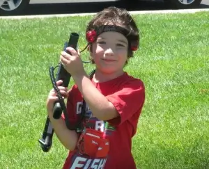 A young boy playing laser tag in a grass field.