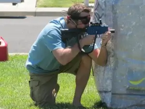 A man with a laser tag tagger in front of a barrier.
