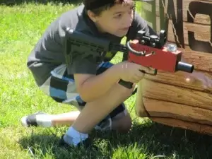 A young boy playing with a laser tag tagger.