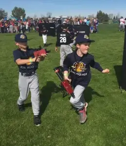 A group of young boys in baseball uniforms playing laser tag.