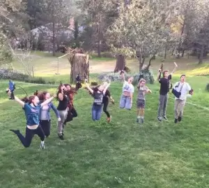 A group of people jumping up and down in the grass at a laser tag party.