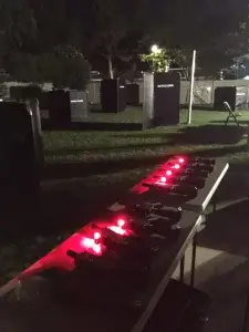 A table with laser tag tagger with red lights in the middle of a grassy area.